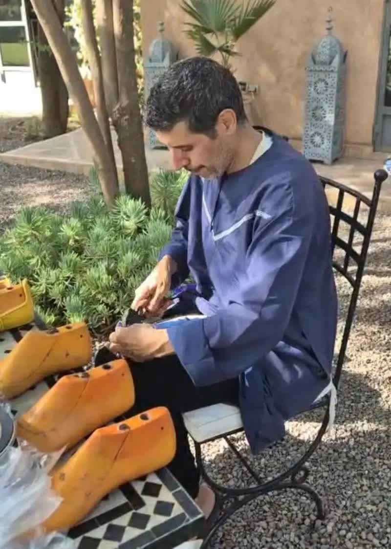 A craftsman finishing a pair of babouches outdoors