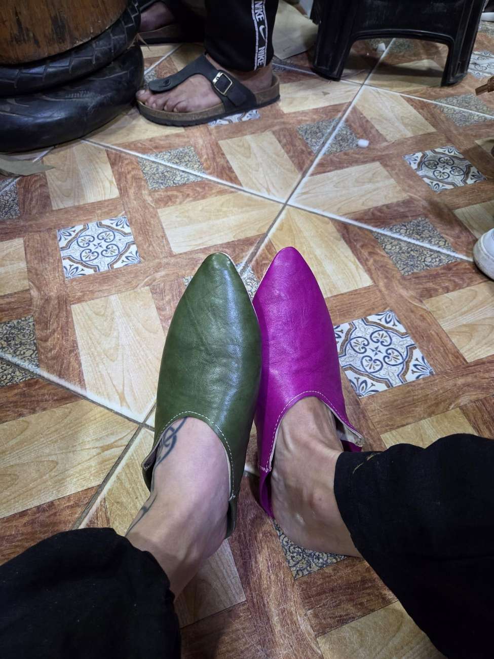 Feet wearing a finished pair of colorful handmade babouches