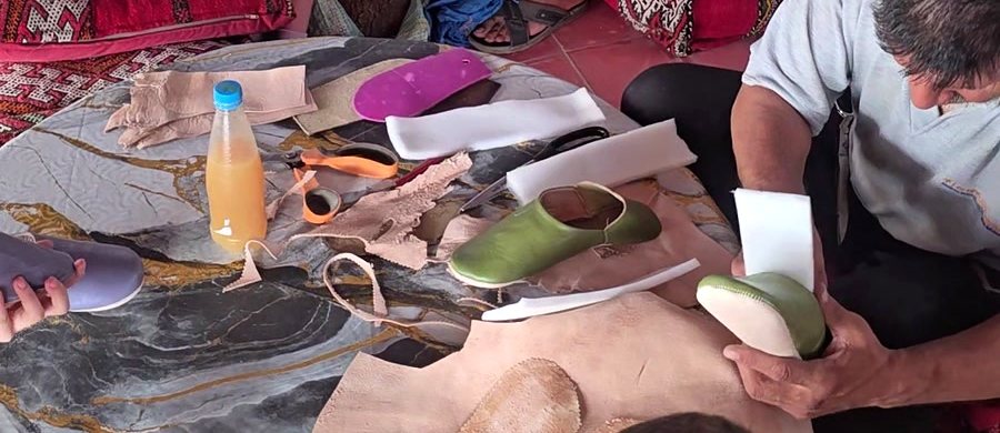 Leather pieces, tools and a finished green babouche on the workshop table