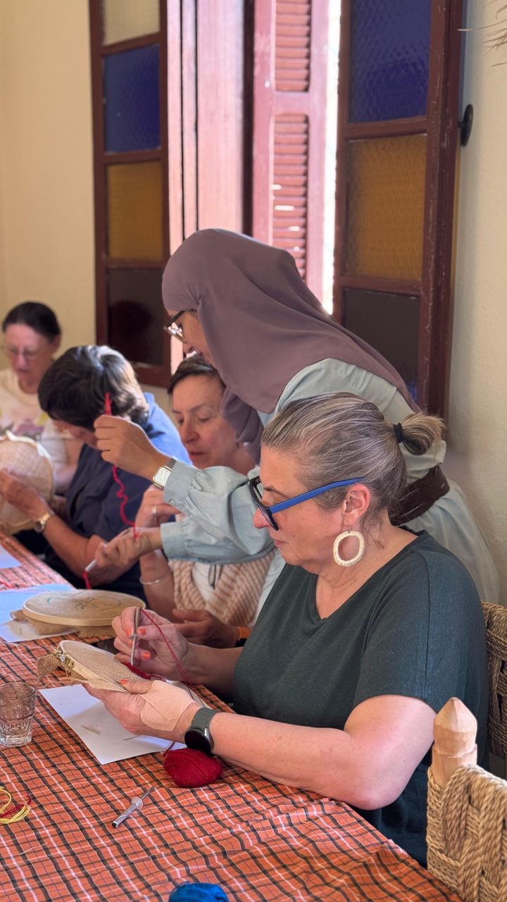 The teacher helping a guest with her embroidery