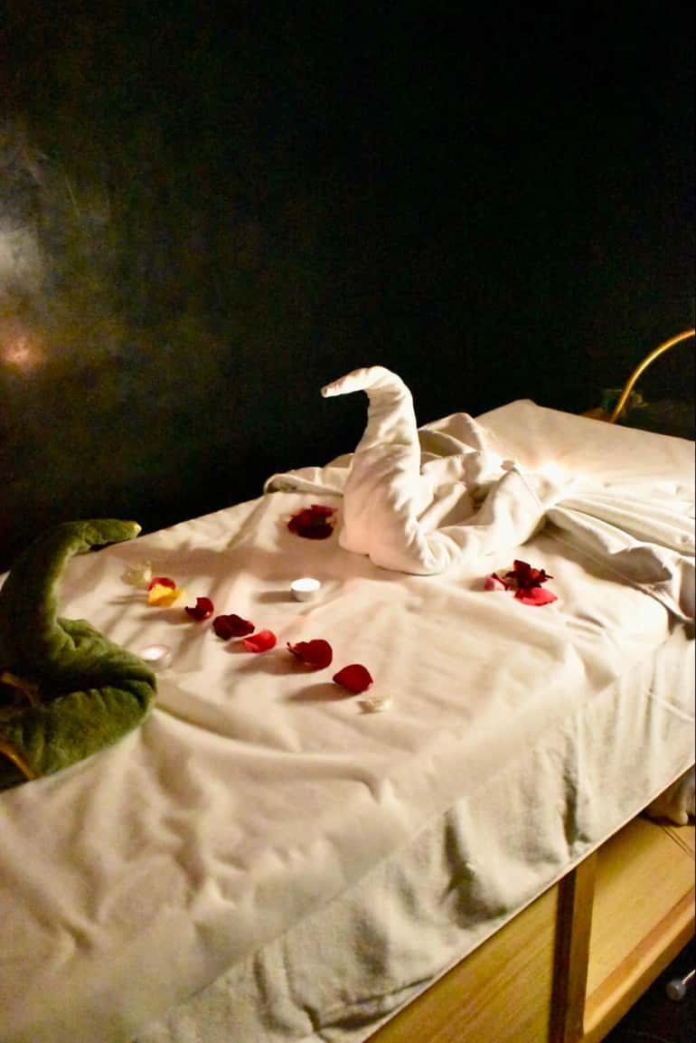 A massage table prepared with rose petals and folded towels